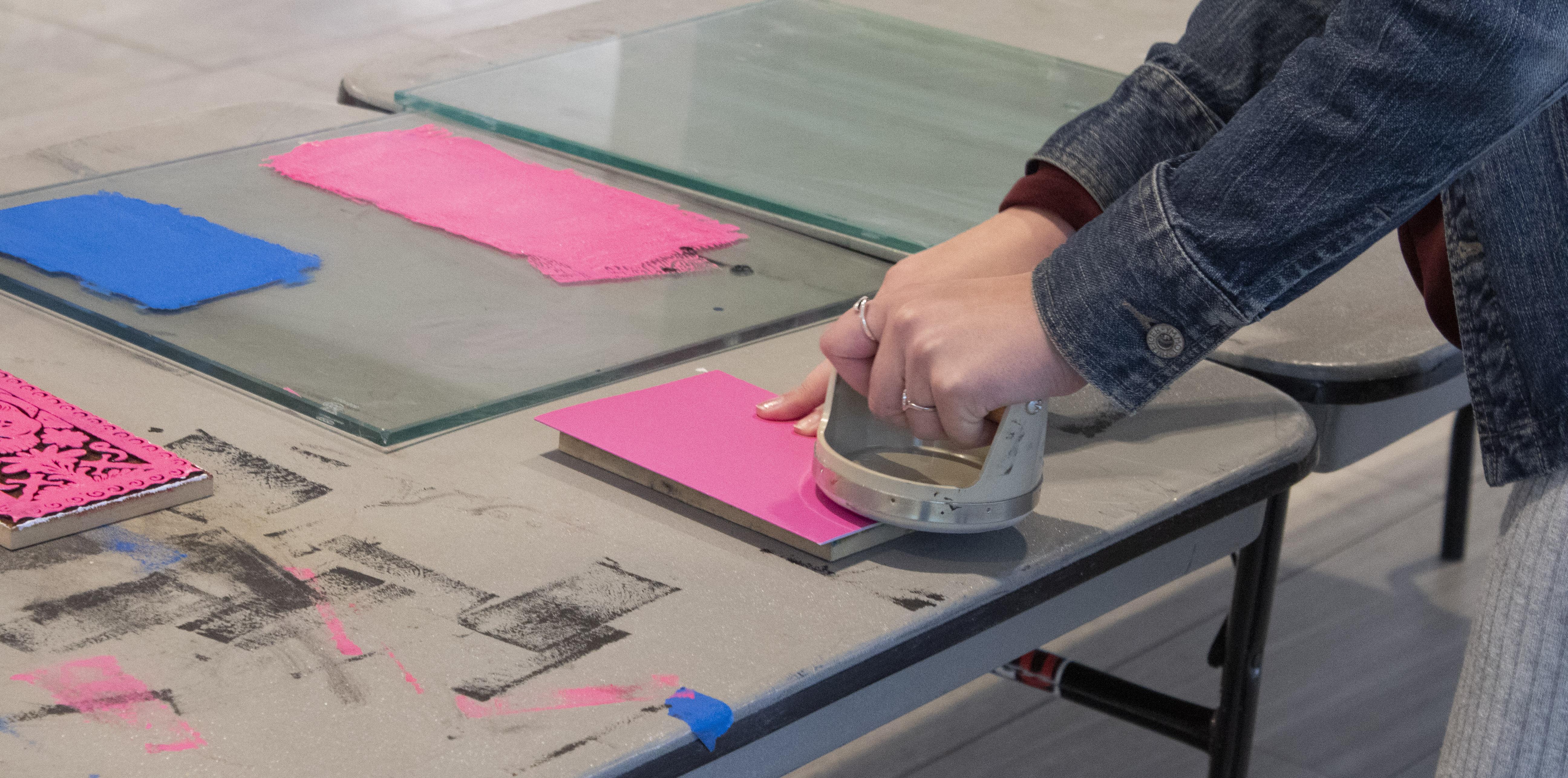 凯瑟琳·卡明斯 帮助参与者制作木版印刷卡片 by showing them the process it takes to make a block print.